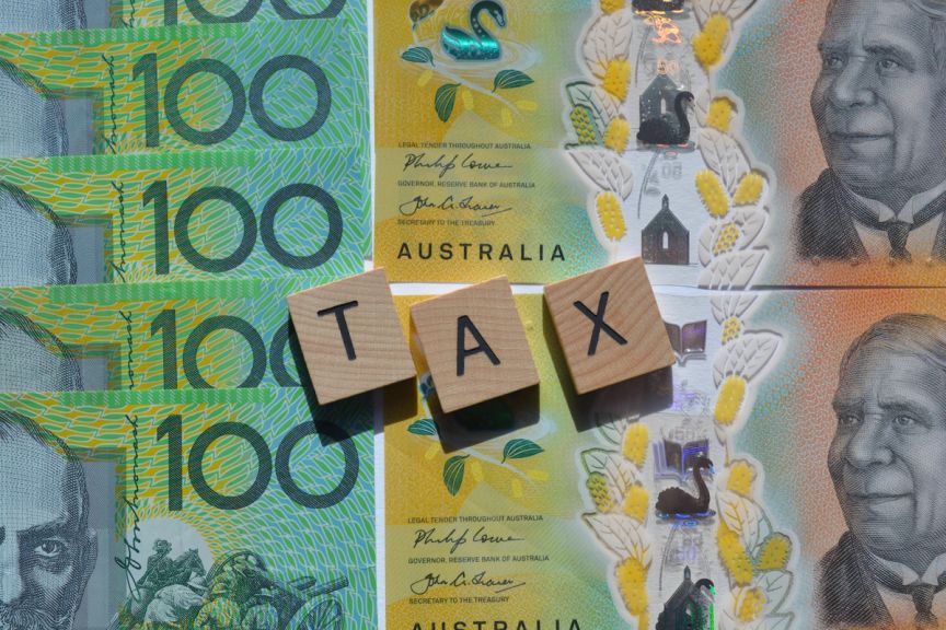 Tax spelled out with building blocks on top of $100 notes