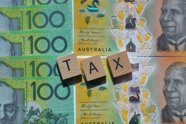Tax spelled out with building blocks on top of $100 notes
