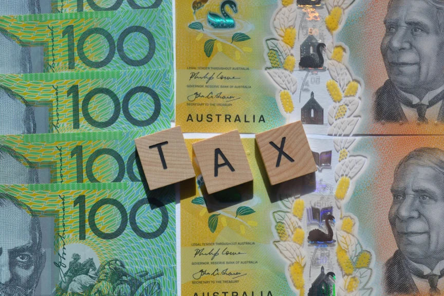 Tax spelled out with building blocks on top of $100 notes
