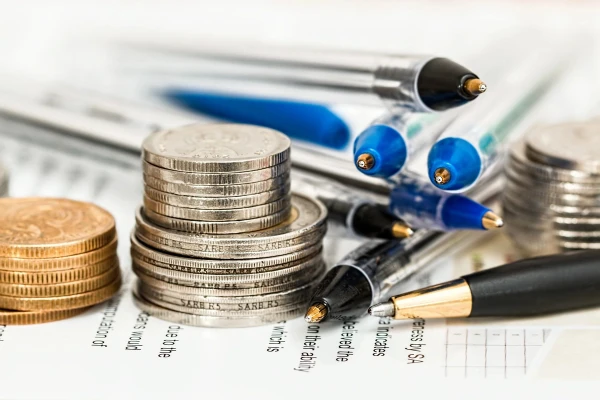 Image of coins and pens stacked on paper